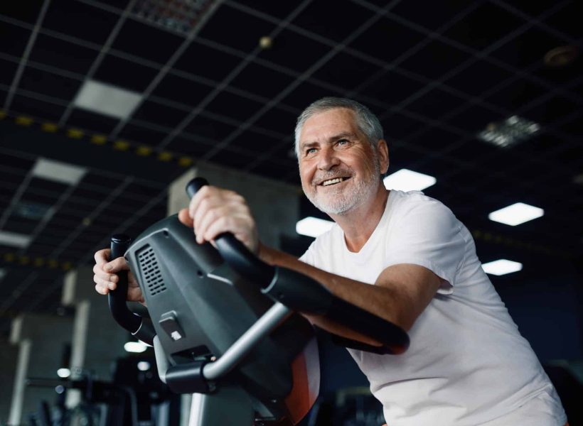 elderly-man-poses-on-exercise-bike-in-gym.jpg